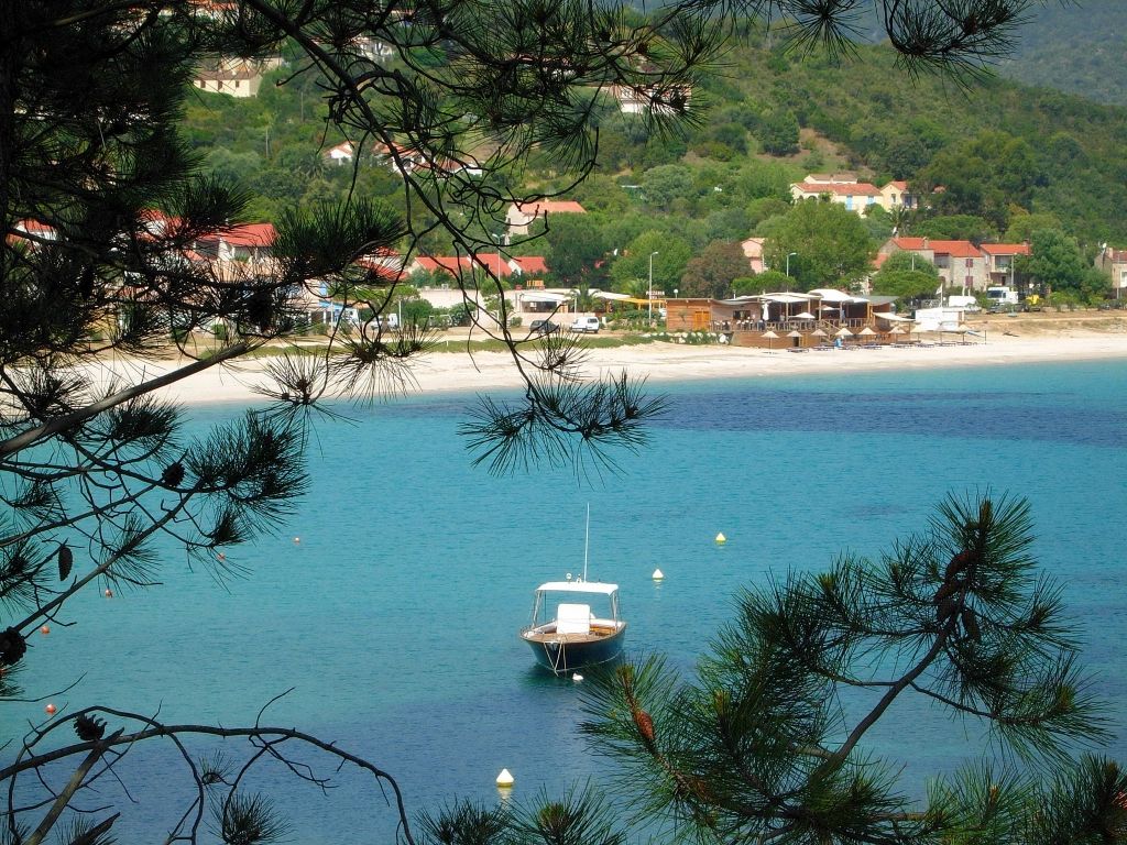 Baie paisible du sud de la Corse avec bateaux au mouillage et collines verdoyantes