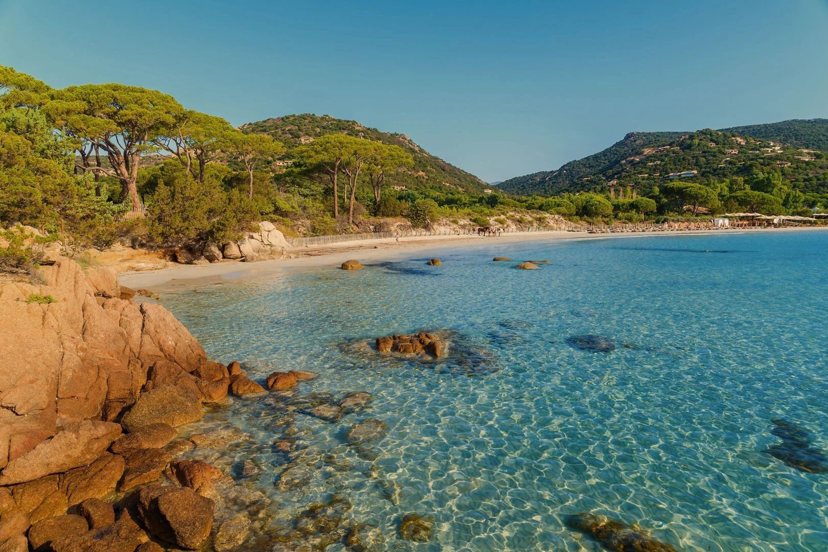 Plage de sable fin avec rochers et eau turquoise en Corse du Sud