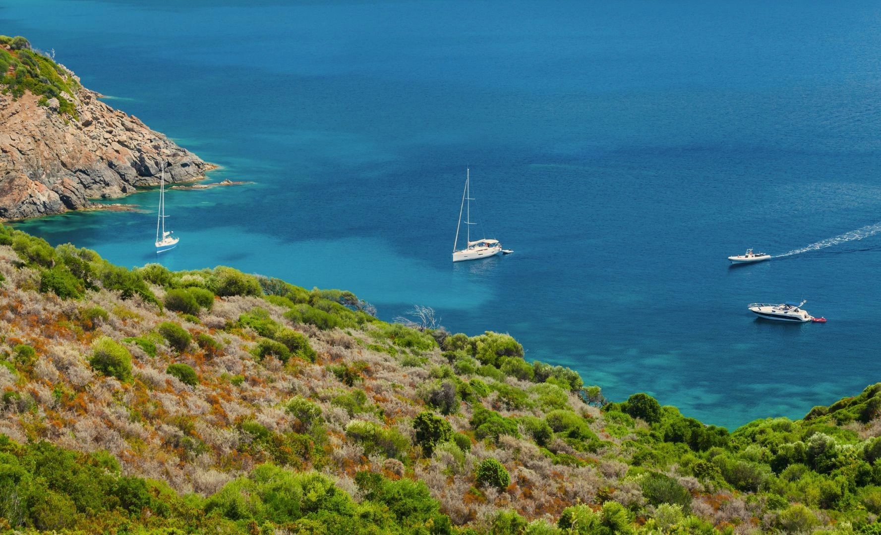 Baie calme avec voiliers au mouillage et collines verdoyantes en Corse du Sud