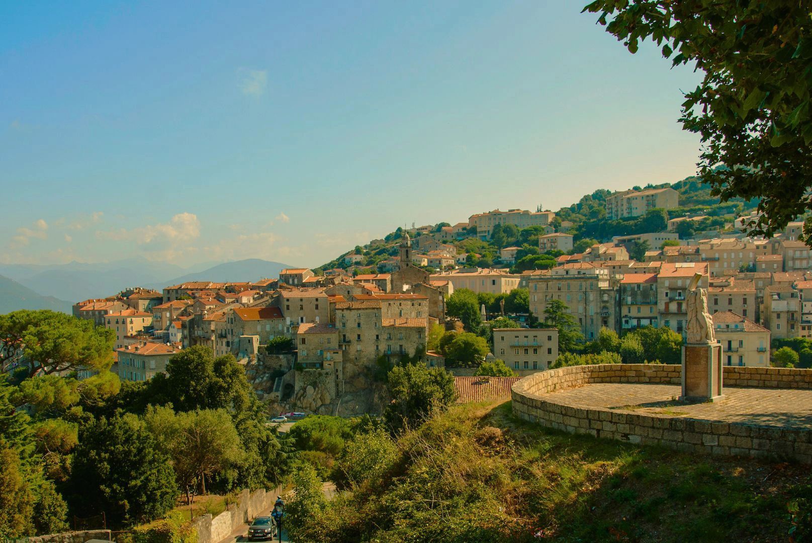 Vue sur un village corse avec maisons en pierre et collines environnantes 