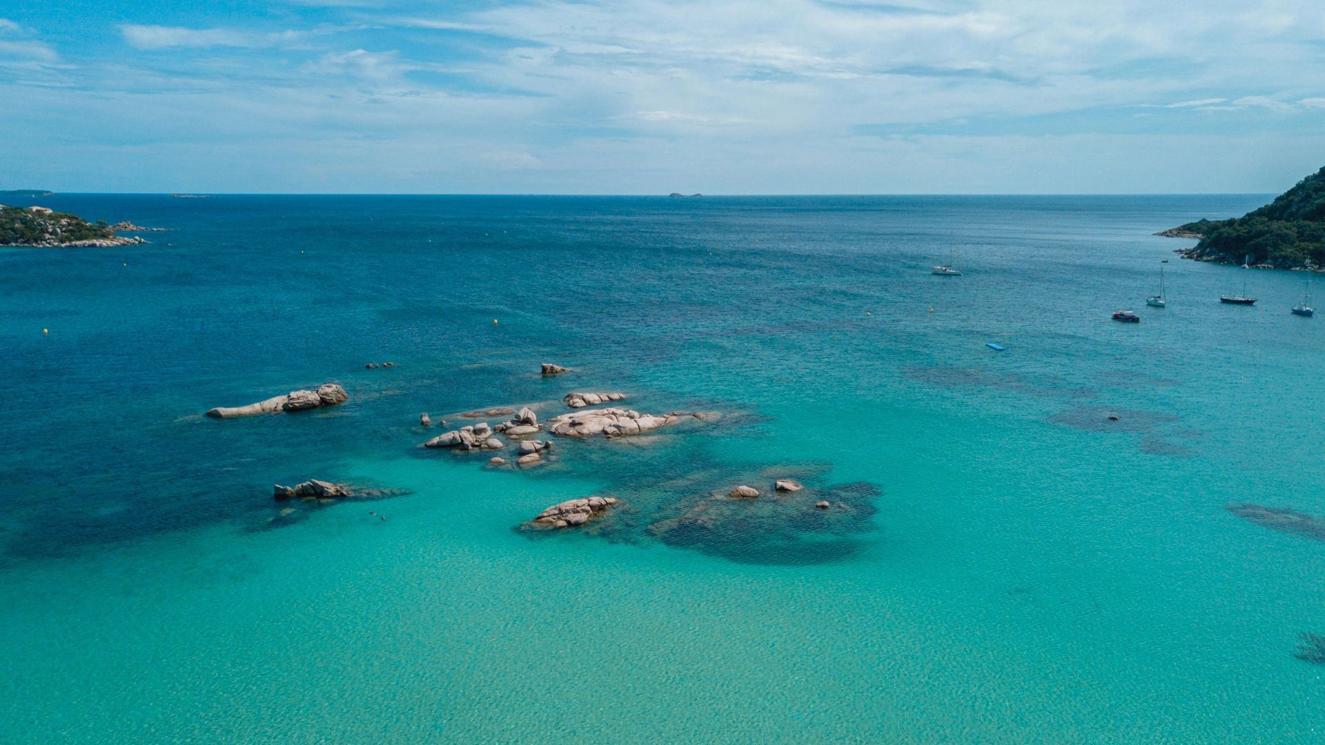 Baie aux eaux turquoise avec rochers immergés en Corse du Sud