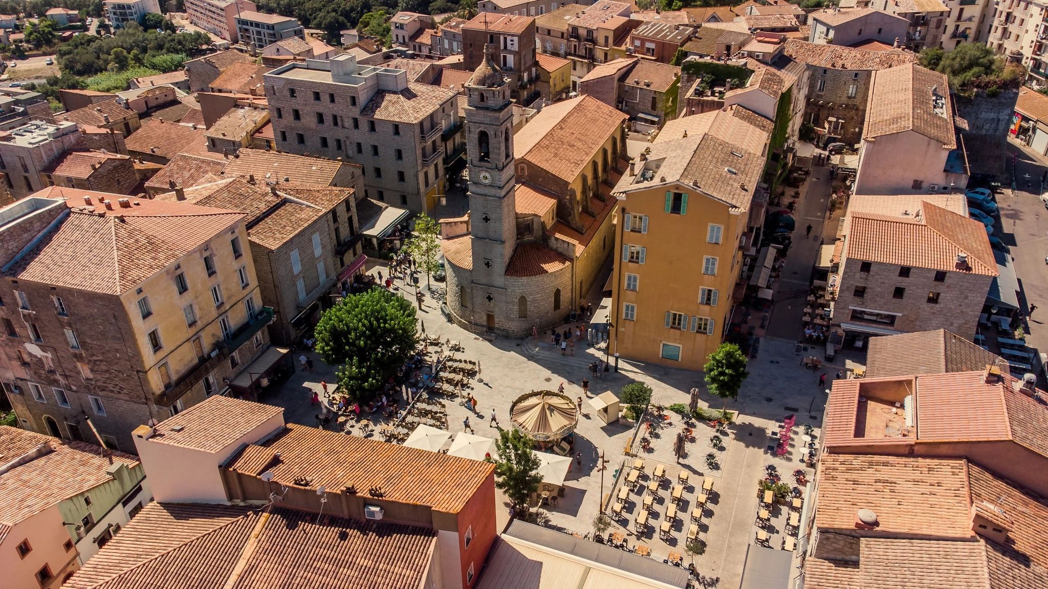 Vue aérienne d’une place centrale entourée de bâtiments anciens dans une ville corse