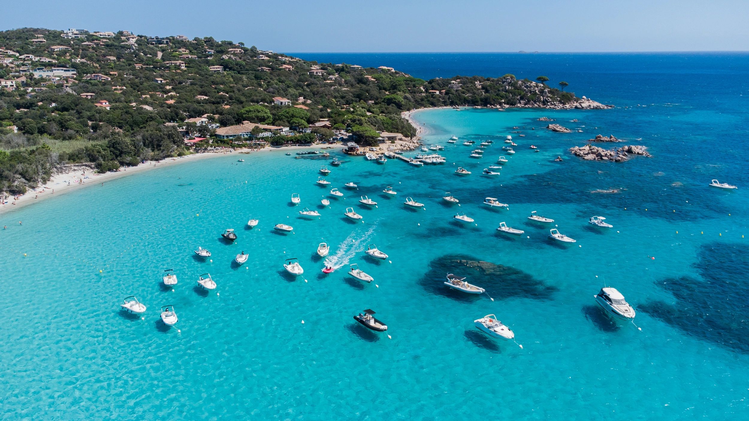 Baie aux eaux turquoise du sud de la Corse avec bateaux au mouillage