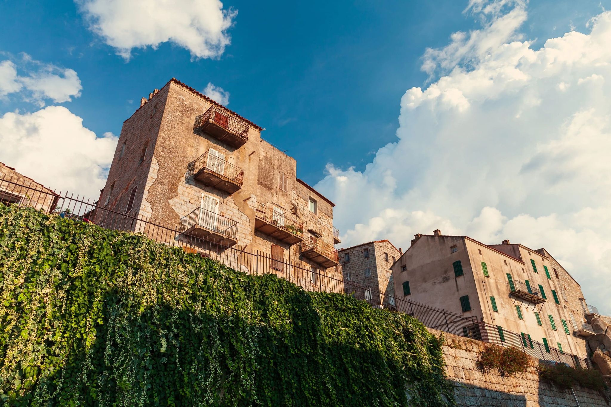 Bâtiments en pierre partiellement recouverts de végétation dans la vieille ville de Bonifacio