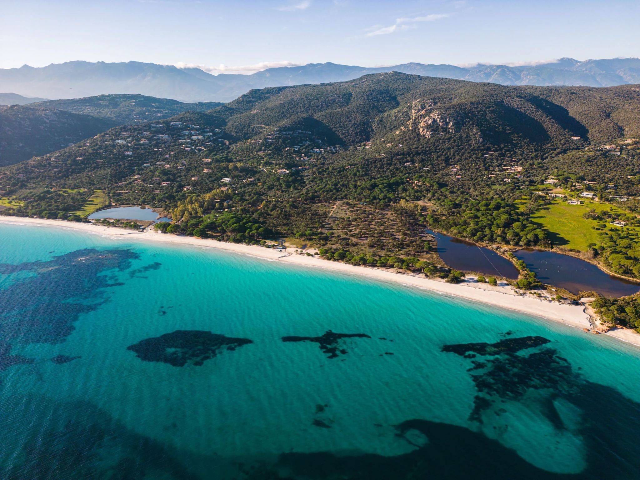 Vue aérienne d’une plage aux eaux turquoise et d’un littoral verdoyant en Corse du Sud