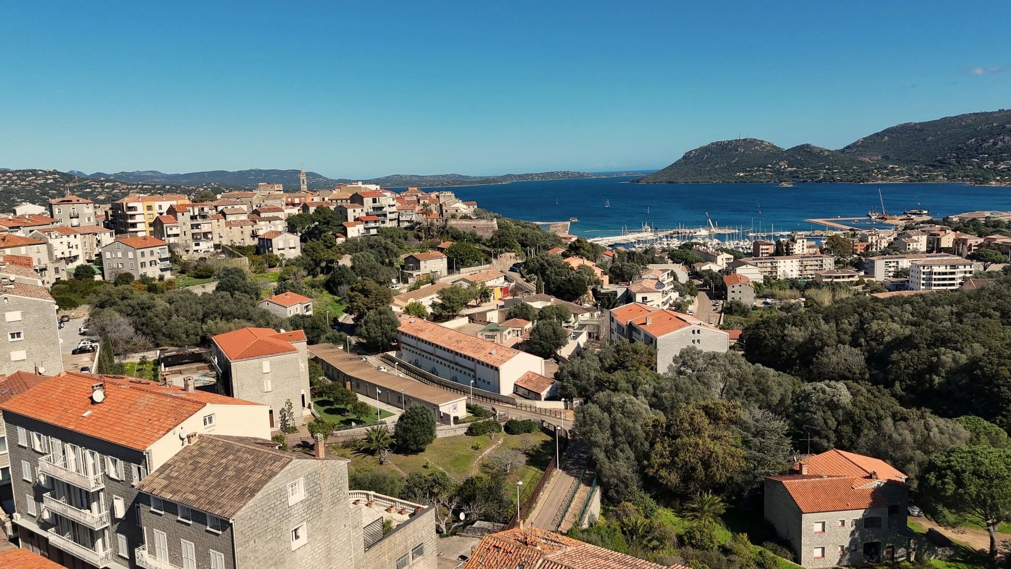 Vue d’un quartier de Porto-Vecchio avec maisons, verdure et golfe en arrière-plan