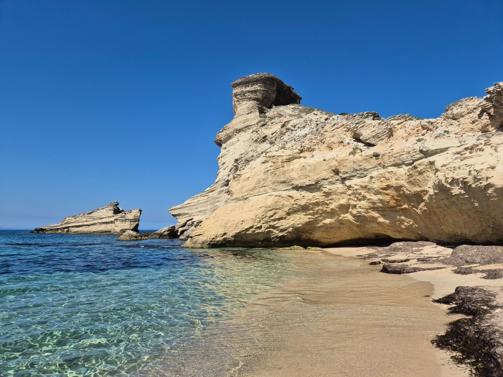 Rocher sculpté et petite plage donnant sur une mer transparente en Corse du Sud